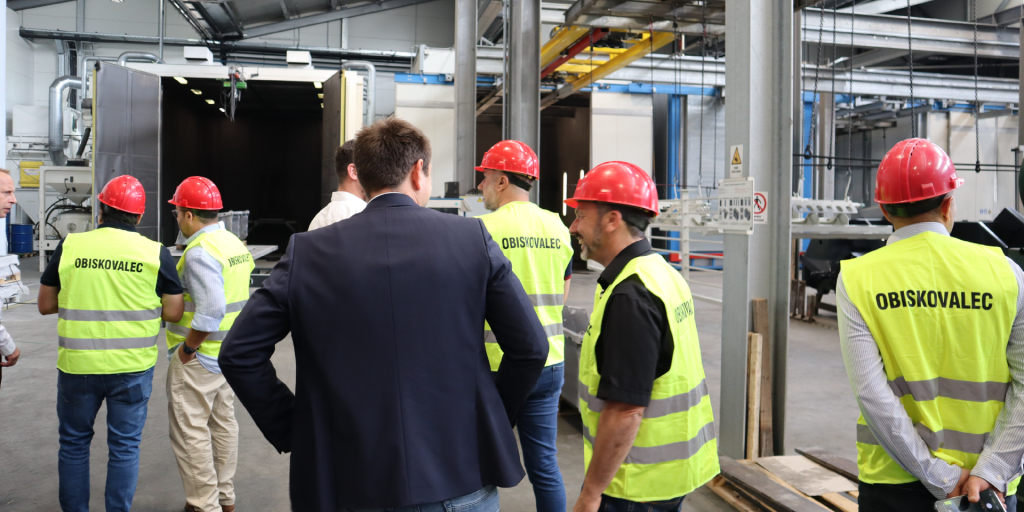 International partners wearing high-visibility visitor vests and helmets discussing operations during the Robust Distributor Event 2026 factory tour.