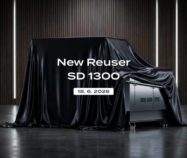 Industrial shredder Robust Reuser SD 1300 dramatically covered with a black cloth in a modern showroom. Image includes the Robust Reuser logo and text: New Reuser SD 1300, 18. 6. 2026.